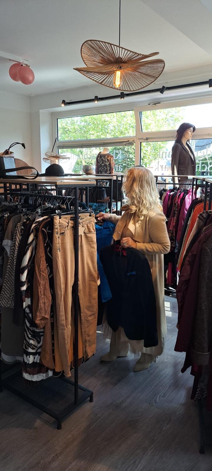 Yvonne stellt im Laden Kleidungsstücke zusammen